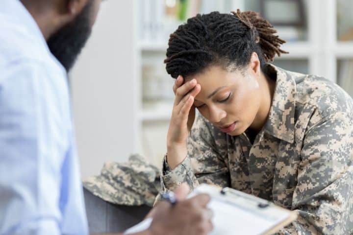 an upset woman in military uniform in a therapy session -PTSD treatment