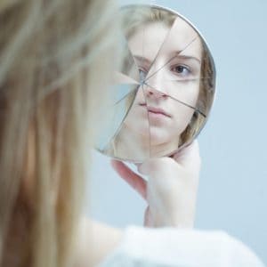 a woman staring into a broken mirror bipolar disorder