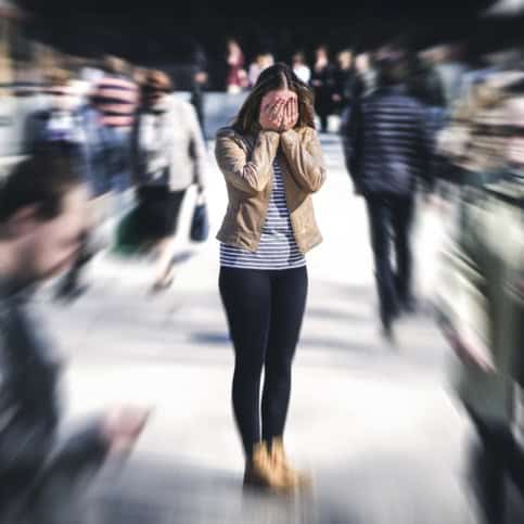 a woman in a large crowd covering her face PTSD Treatment