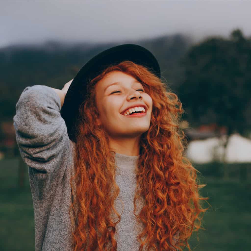 a woman with red curly hair looking towards the sky