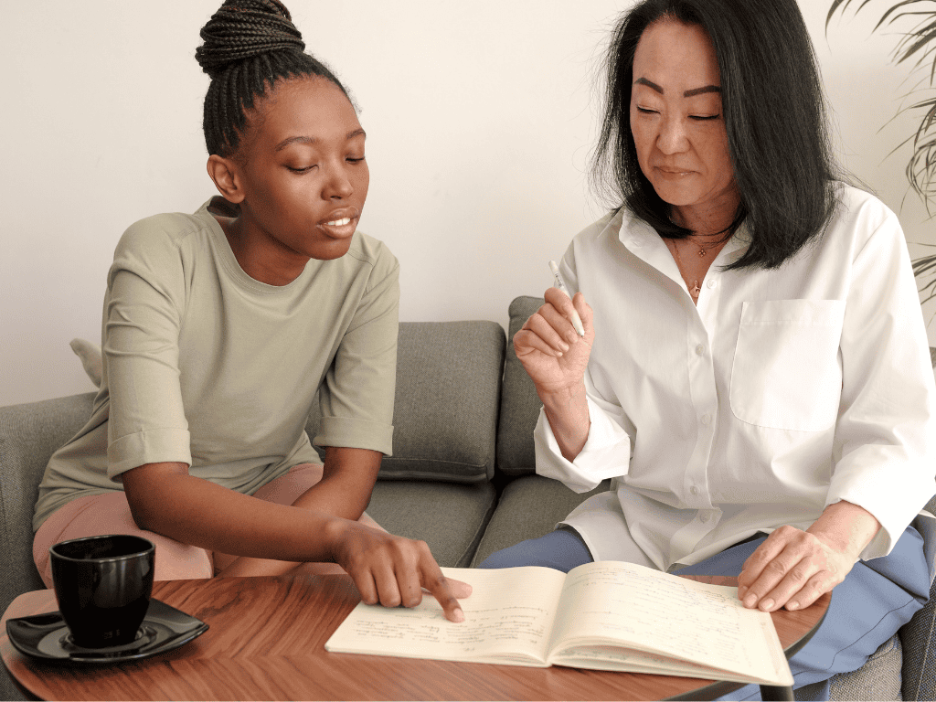 two diverse women looking at a book neurodivergent therapy