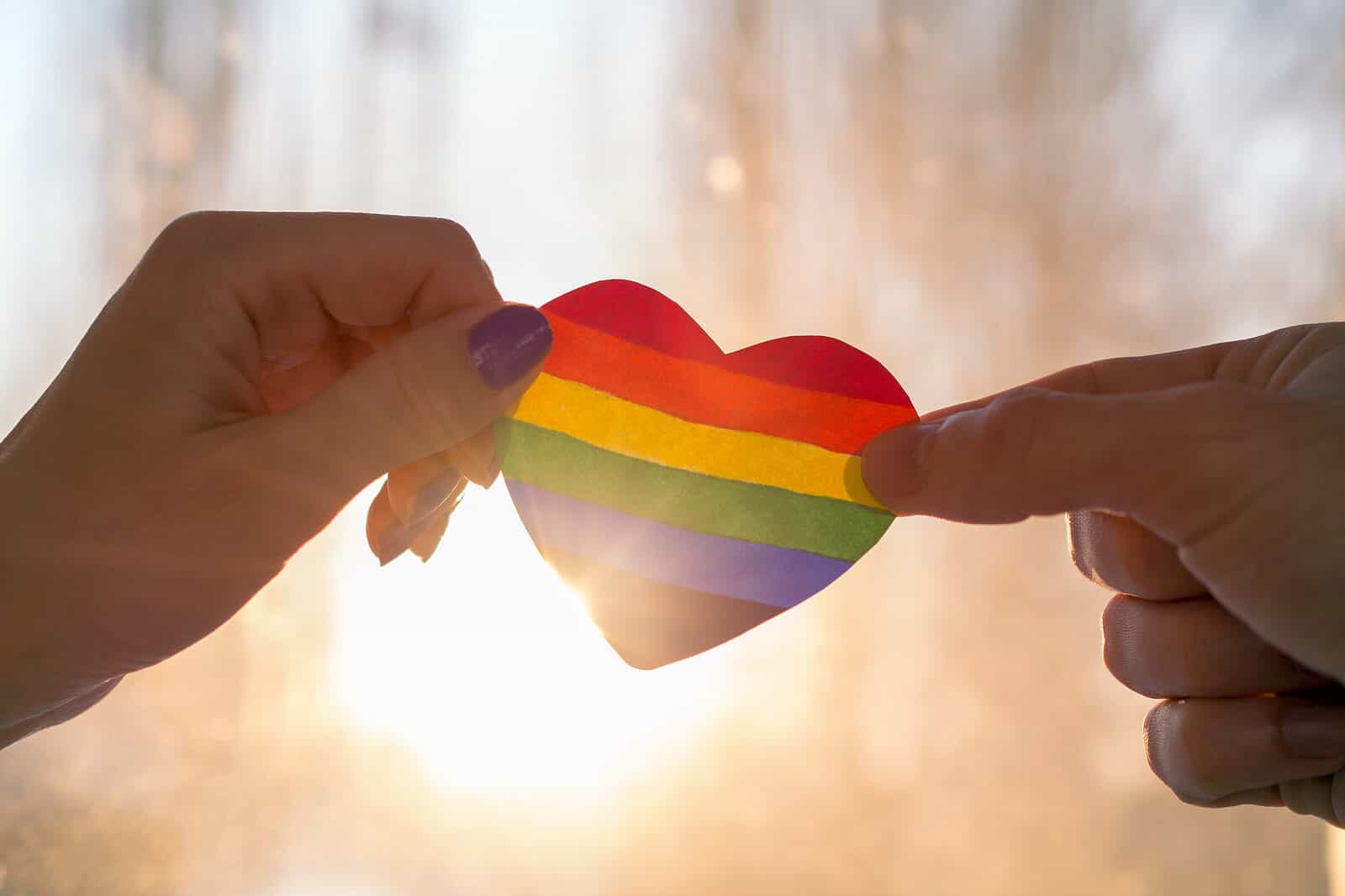 two hands holding a rainbow heart start LGBTQIA+ therapy