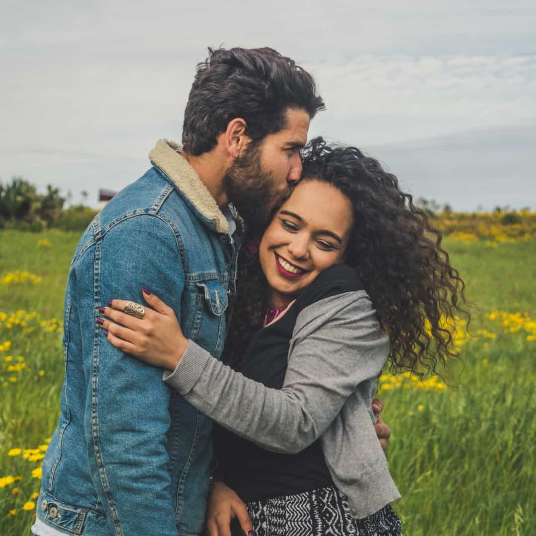 Image of a couple embracing while the male kisses the female's temple. Are you interested in forming a stronger bond in couples therapy and marriage counseling in North Carolina