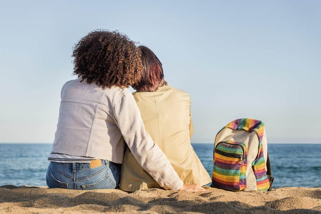 Image of a lesbian couple sitting on the beach together showing the benefits of going to couples therapy in North Carolina with a couples therapist. Marriage counseling is for all partnerships at Resilient mind. Regardless of race, sexual orientation, or gender.