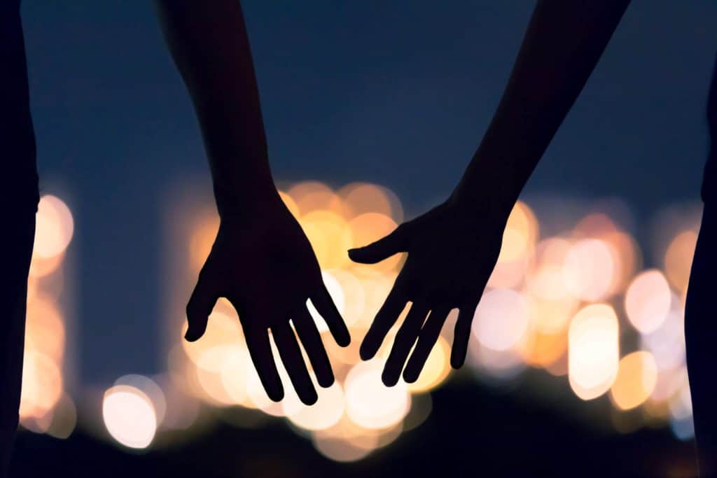 A close up of two hands near one another against the night sky, representing the relationship cultivated via marriage counseling in Asheville, NC. Contact a couples therapist in North Carolina to learn more about our services including marriage counseling in Asheville, NC.