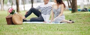 A couple smile with one another while sitting on a picnic blanket in a park. A couples therapist in North Carolina can offer date ideas to help cultivate stronger bonds. Learn more about couples therapy in North Carolina, marriage counseling in Asheville, NC, and other services.