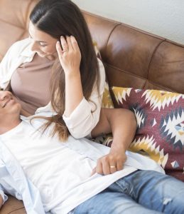 A couple lay on a couch while smiling at one another. This could represent the close bond a couples therapist in North Carolina can cultivate. Learn more about couples therapy in North Carolina and the other services offered.