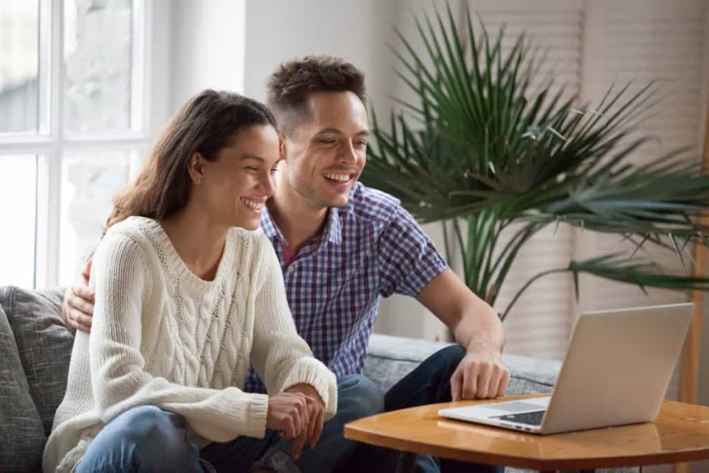 Happy-Young-Couple-Smiling-at-Laptop