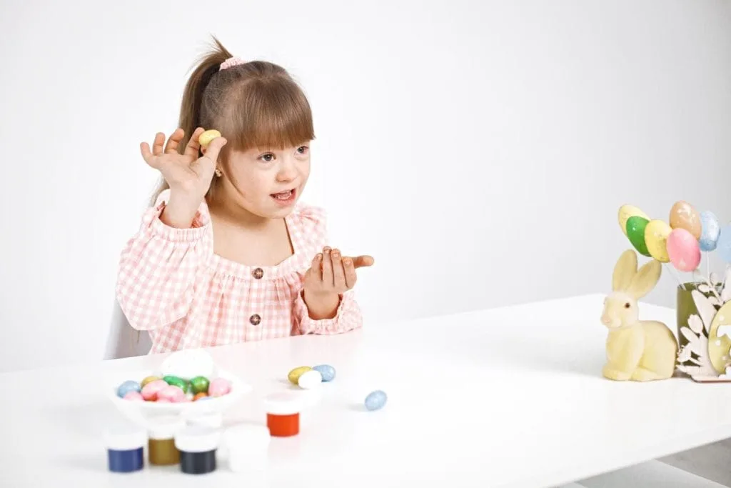 portrait-charming-girl-with-down-syndrome-playing-with-easter-colored-eggs