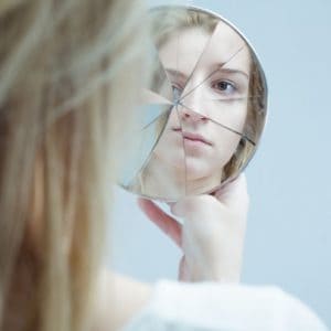 a woman staring into a broken mirror bipolar disorder